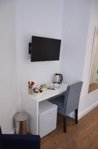 einen weißen Schreibtisch mit Stuhl und einen TV an der Wand in der Unterkunft Edificio Charles 202 in Funchal