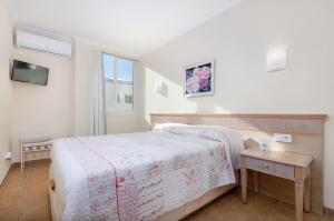 ein Schlafzimmer mit einem Bett, einem Tisch und einem Fernseher in der Unterkunft Bonanza 5 in Colonia Sant Jordi