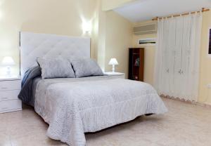 - une chambre avec un grand lit et un couvre-lit blanc dans l'établissement Apartamentos La Relojera 2, à Jarandilla de la Vera