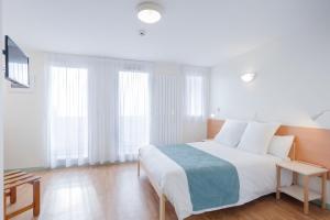 a white bedroom with a large bed with white pillows at Centre Jean XXIII in Annecy