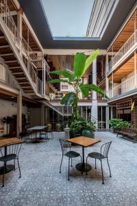 a room with tables and chairs and a plant in it at Nanda Heritage Hotel in Bangkok