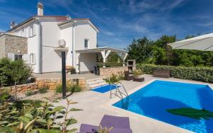 a villa with a swimming pool in front of a house at Holiday house CIRIK in Kras