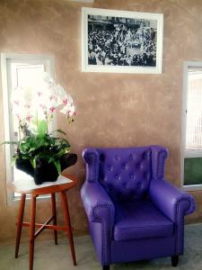 une chaise violette et une table avec un vase de fleurs dans l'établissement Kesorn Boutique Residence at 8 Riew, à Chachoengsao