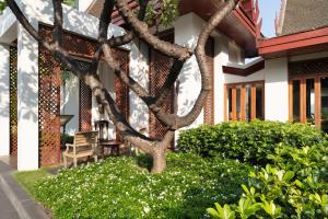 a tree in front of a house with white flowers at The Sukhothai Bangkok - SHA Plus Certified in Bangkok