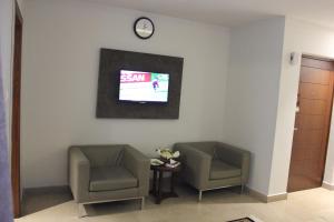 2 Stühle in einem Zimmer mit einem TV an der Wand in der Unterkunft Hotel One Super, Islamabad in Islamabad