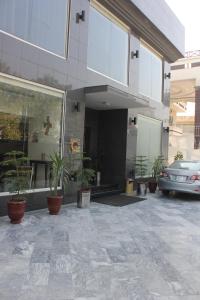 ein Auto, das außerhalb eines Gebäudes mit Topfpflanzen parkt in der Unterkunft Hotel One Super, Islamabad in Islamabad