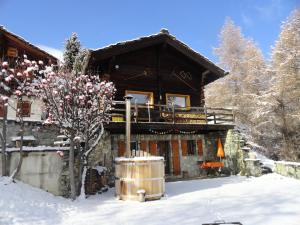 une cabane en rondins dans la neige avec un tonneau dans l'établissement Grand Pra, à Les Haudères