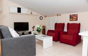a living room with two red chairs and a tv at Apartamentos La Relojera 2 in Jarandilla de la Vera