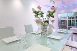 uma sala de jantar com uma mesa de vidro com flores num vaso em Kamelly em Badalona