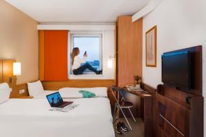 a hotel room with two beds and a laptop on a window at Ibis Praha Mala Strana in Prague
