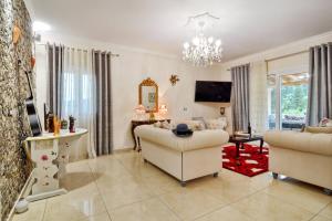a living room with a couch and chairs and a television at Villa Zoi in Pelekas
