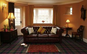sala de estar con sofá de cuero marrón y ventana en Find Me Out Holiday Cottage, en Dalmellington