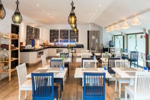 a restaurant with white tables and blue chairs at Hotel San Sebastián Orly, Affiliated by Meliá in Donostia-San Sebastián