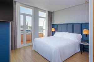 a bedroom with a white bed and a large window at Hotel San Sebastián Orly, Affiliated by Meliá in Donostia-San Sebastián