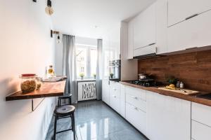 a kitchen with white cabinets and a wooden counter top at Theatre Apartment - Apartament przy Rynku w Głogowie in Głogów