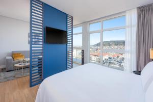 a bedroom with a blue wall with a tv and a bed at Hotel San Sebastián Orly, Affiliated by Meliá in Donostia-San Sebastián
