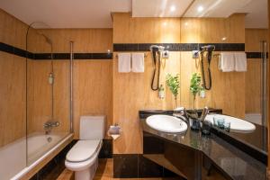 a bathroom with two sinks and a tub and a toilet at Hotel San Sebastián Orly, Affiliated by Meliá in Donostia-San Sebastián