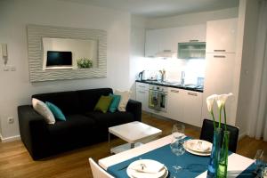 a living room with a black couch and a kitchen at Apartment Akvarel in Split