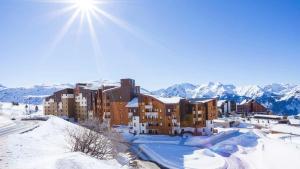 ein Gebäude im Schnee mit Bergen im Hintergrund in der Unterkunft Résidence Les Bergers in L'Alpe-d'Huez