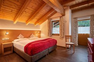 um quarto com uma cama grande num quarto com tectos em madeira em Hotel Pensione Veneranda em Corvara in Badia