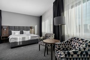 ヴロツワフにあるDB Hotel Wrocławのベッド、テーブル、椅子が備わるホテルルームです。