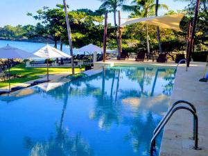 a swimming pool with blue water and umbrellas at Comfortable Apartment in Caribbean Paradise in Sosúa