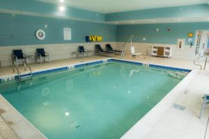 a swimming pool in a gym with chairs and tables at Holiday Inn Express & Suites - Orland Park Mokena, an IHG Hotel in Mokena