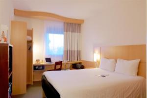 a hotel room with a large bed and a desk at Ibis Cotonou in Cotonou