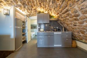 cocina con pared de piedra, fregadero y nevera en Loft in the wall en ‘Akko