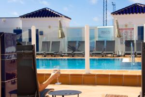 a person holding a glass of wine next to a swimming pool at TAO El Cotillo - VV in El Cotillo