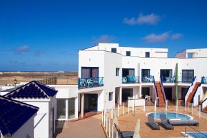 a large white building with a patio and a swimming pool at TAO El Cotillo - VV in El Cotillo