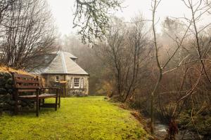 a bench in front of a house in the woods at Find Me Out Holiday Cottage in Dalmellington