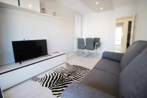 ein Wohnzimmer mit Fernseher und Zebrateppich in der Unterkunft Family Deluxe Apartment Beach in Castelldefels