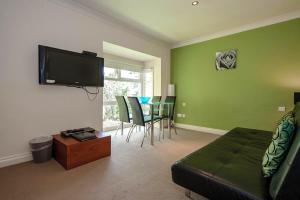 a living room with a television and a table with chairs at Bagshaw Lodge in Bakewell