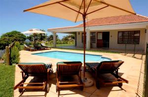 een zwembad met twee stoelen en een parasol bij Pearl Cottage in Durban