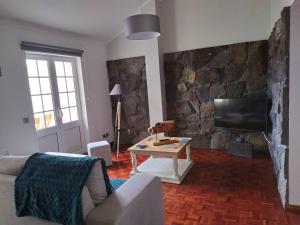 uma sala de estar com uma parede de pedra e uma televisão em Margarida House - Stone Apartment em Ribeira Grande