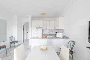 eine Küche mit weißen Schränken und einem Tisch und Stühlen in der Unterkunft Estela Maris in Nerja