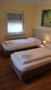 three beds in a room with a window at Gästehaus Schmitt in Erlangen