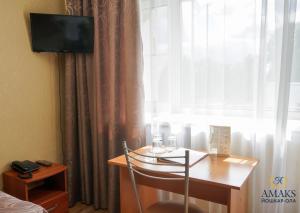 a room with a desk and a window with a television at AMAKS City Hotel in Yoshkar-Ola