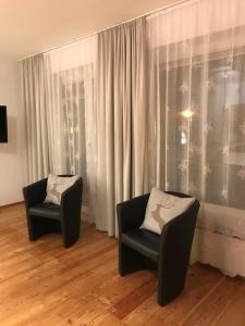 dwa krzesła siedzące w pokoju z zasłonami w obiekcie Appartement Berger w mieście Zell am See