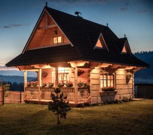 a small log cabin with a black roof at Domek Folkowa Chata in Poronin