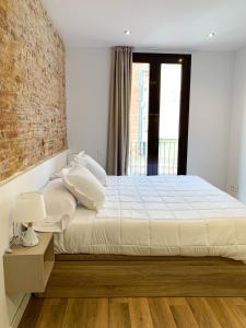 um quarto com uma cama e uma parede de tijolos em LucasLand Apartments Barcelona em Barcelona
