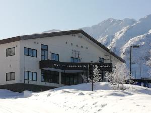 un edificio en la nieve frente a una montaña en Ryounkaku, en Kami-furano