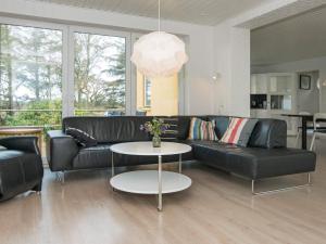 uma sala de estar com um sofá de couro preto e uma mesa em 10 person holiday home in R m em Bolilmark