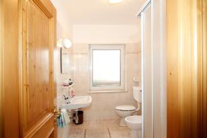 baño con lavabo y aseo y ventana en Appartamenti Lezuo Iris en Arabba