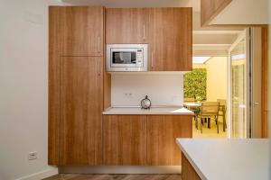 eine Küche mit Holzschränken und einer Mikrowelle in der Unterkunft Bright apartment near Casa de Campo by Batuecas in Madrid