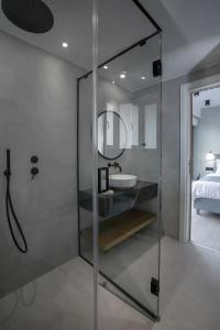 uma casa de banho com uma cabina de duche em vidro e um lavatório. em Acropolis Golden Suites by GHH em Atenas