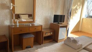 a room with a mirror and a desk with a tv at Sariza Spring Hotel in Andros