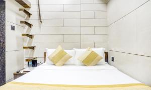 a bedroom with a white bed with yellow pillows at Hotel Rooms Dadar near Station in Mumbai