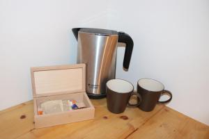 a coffee pot and two mugs and a box on a table at New Fontana Rooms in Como